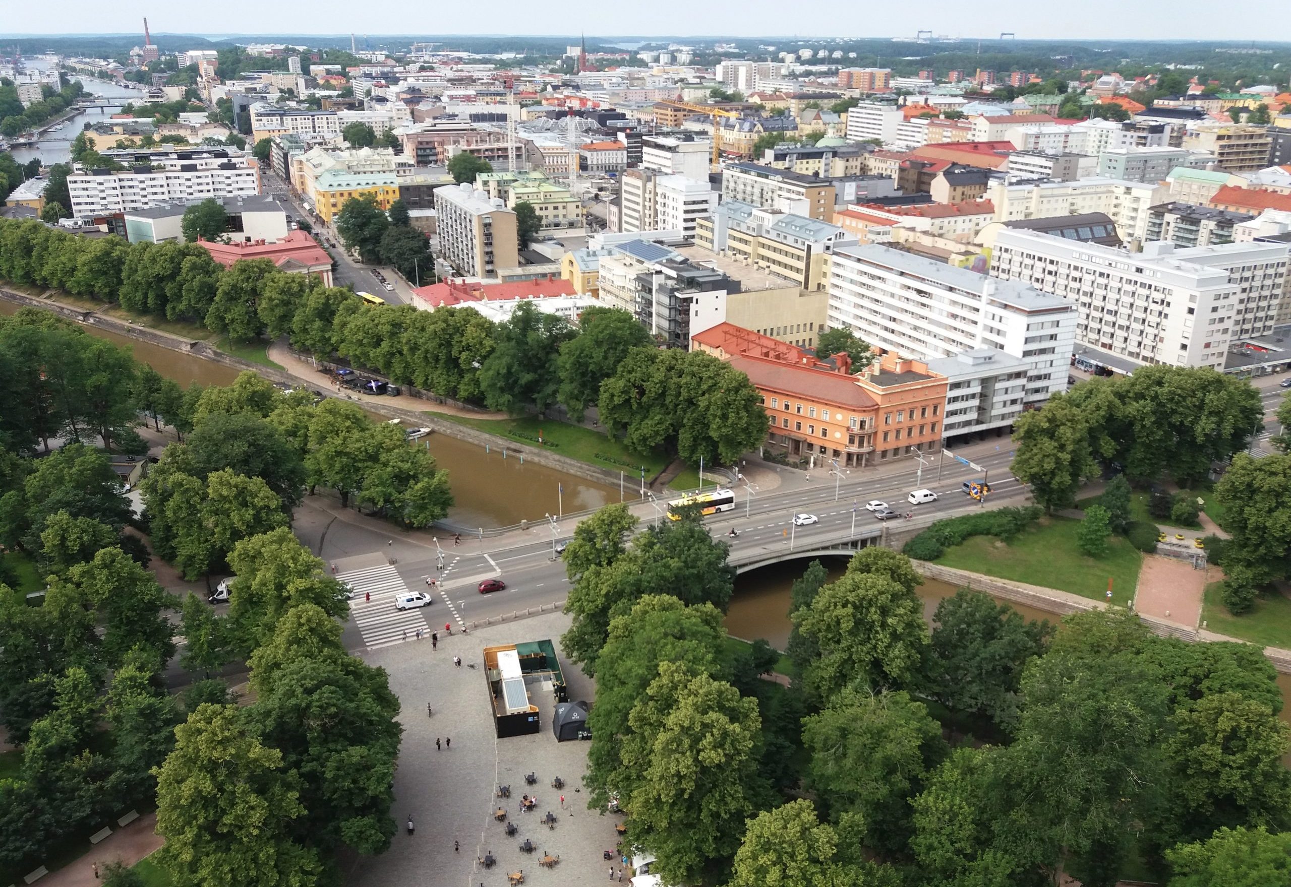 Kuvassa on läntisen Turun keskustaa. Puistojen vihreitä puita, erivärisiä vaaleita kerrostaloja ja keskellä virtaa Aurajoki.