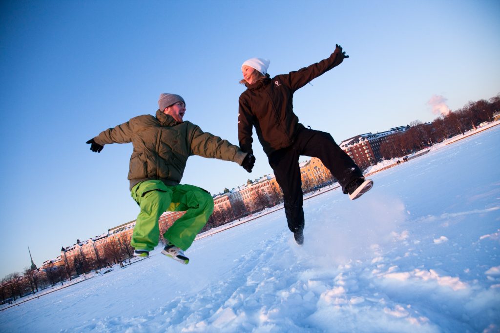 mies ja nainen hyppäävät ilmaan lumisessa maisemassa