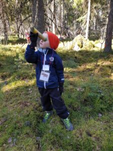 Lapsi kiikaroi metsässä.