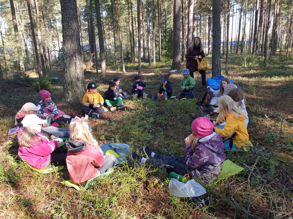 TIkankolon luontokoulun lapset istuvat ringissä metsässä.
