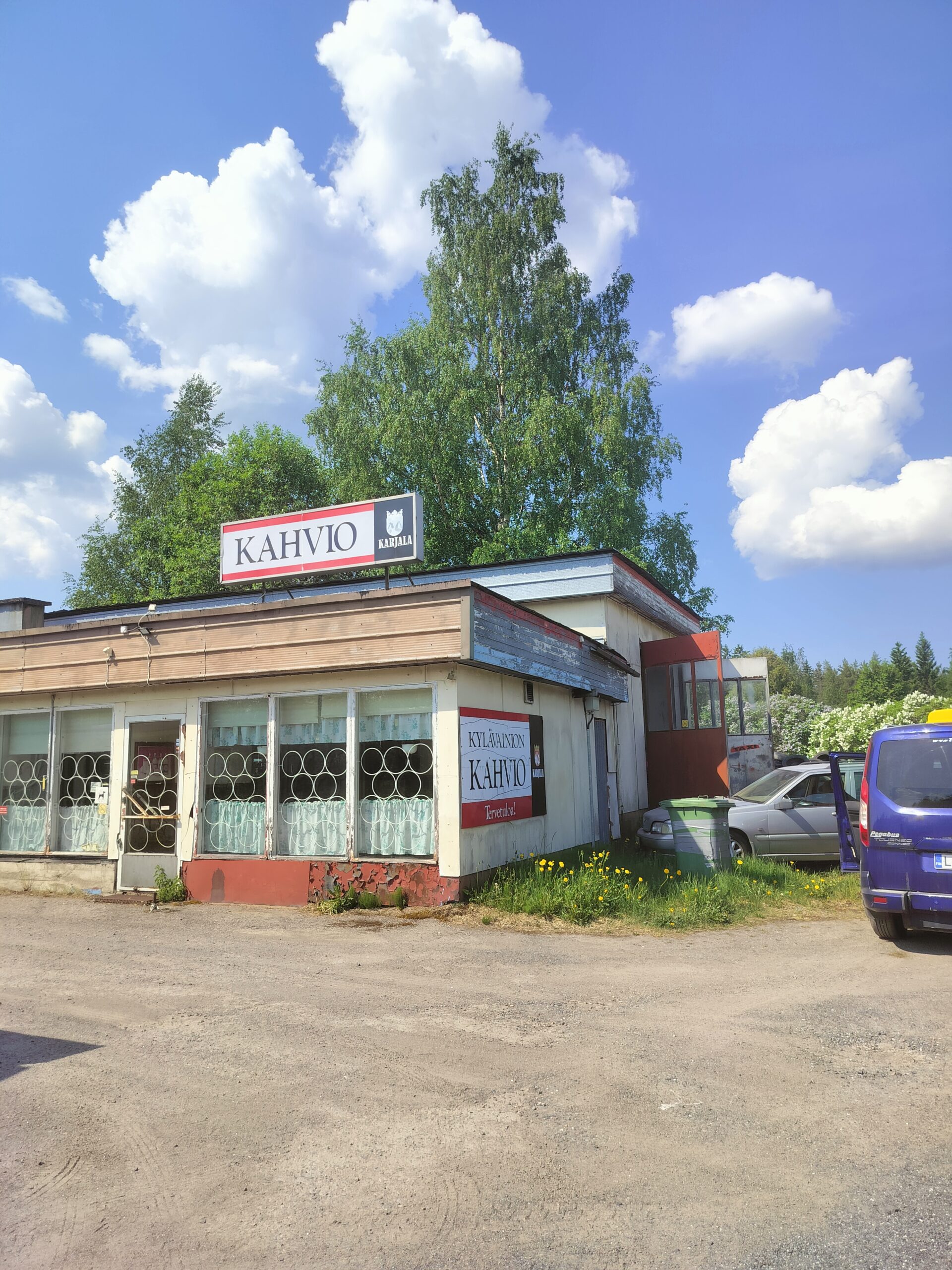 Valkoinen laatikkomainen rakennus, jonka etuseinä sioja ikkunoita. Tasakatto.